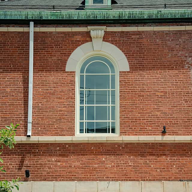 An arch top aluminum window in a brick building.